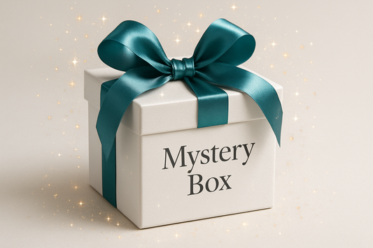 White box with a teal bow and text that says mystery box. add some sparkle and make the box look desirable, like you just cant wait to get it open and see the goods inside. the box should have an elegant feel to it